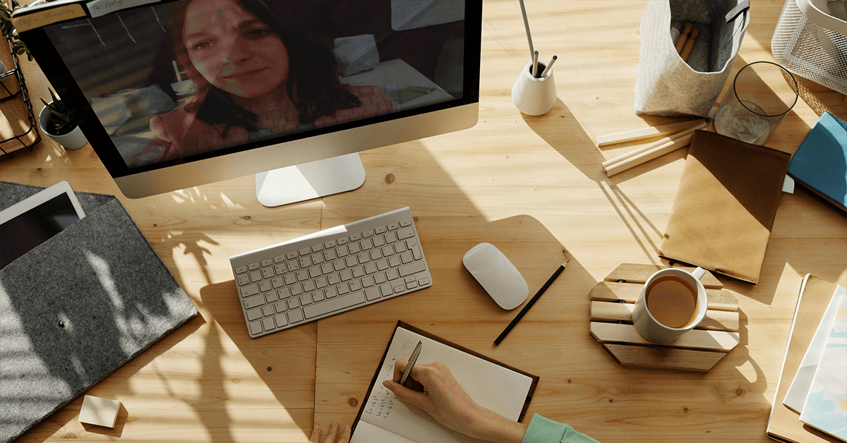Overhead view of a remote professional on a video call, writing notes, representing the strategic, remote CFO services and virtual accounting support for businesses.